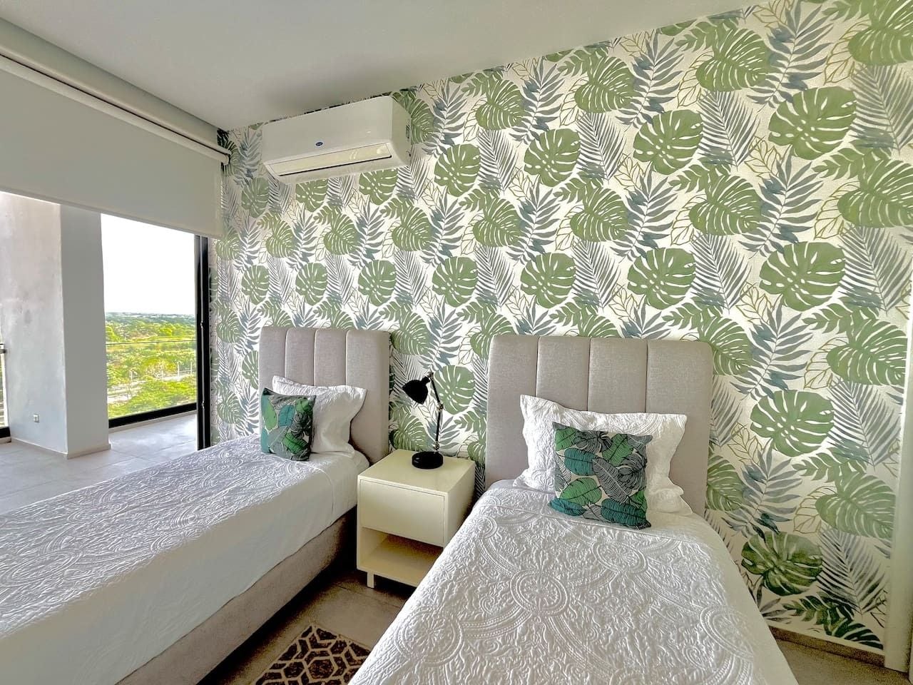 Une chambre d’hôtel avec deux lits, une table de chevet et une fenêtre donnant sur un beau paysage.