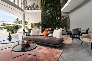 A modern lounge area with a sofa, chairs, a coffee table, and a vertical garden. - Luxury Bolongo Beachfront Apartment in Punta Mita (Corral del Risco)