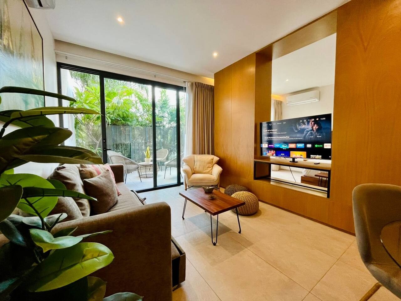 Un salon moderne comprenant un canapé, un fauteuil, une table basse et un téléviseur à écran plat fixé au mur.