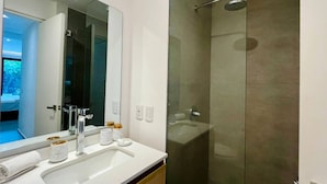 Un bagno moderno con uno specchio grande, un lavandino bianco e una cabina doccia in vetro.