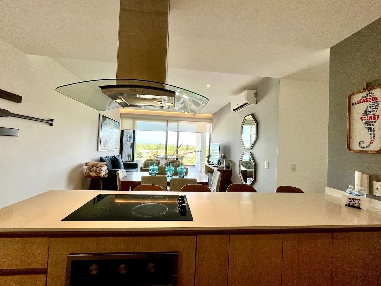 A modern kitchen with a central island, a large window, and a view of the outdoors.
