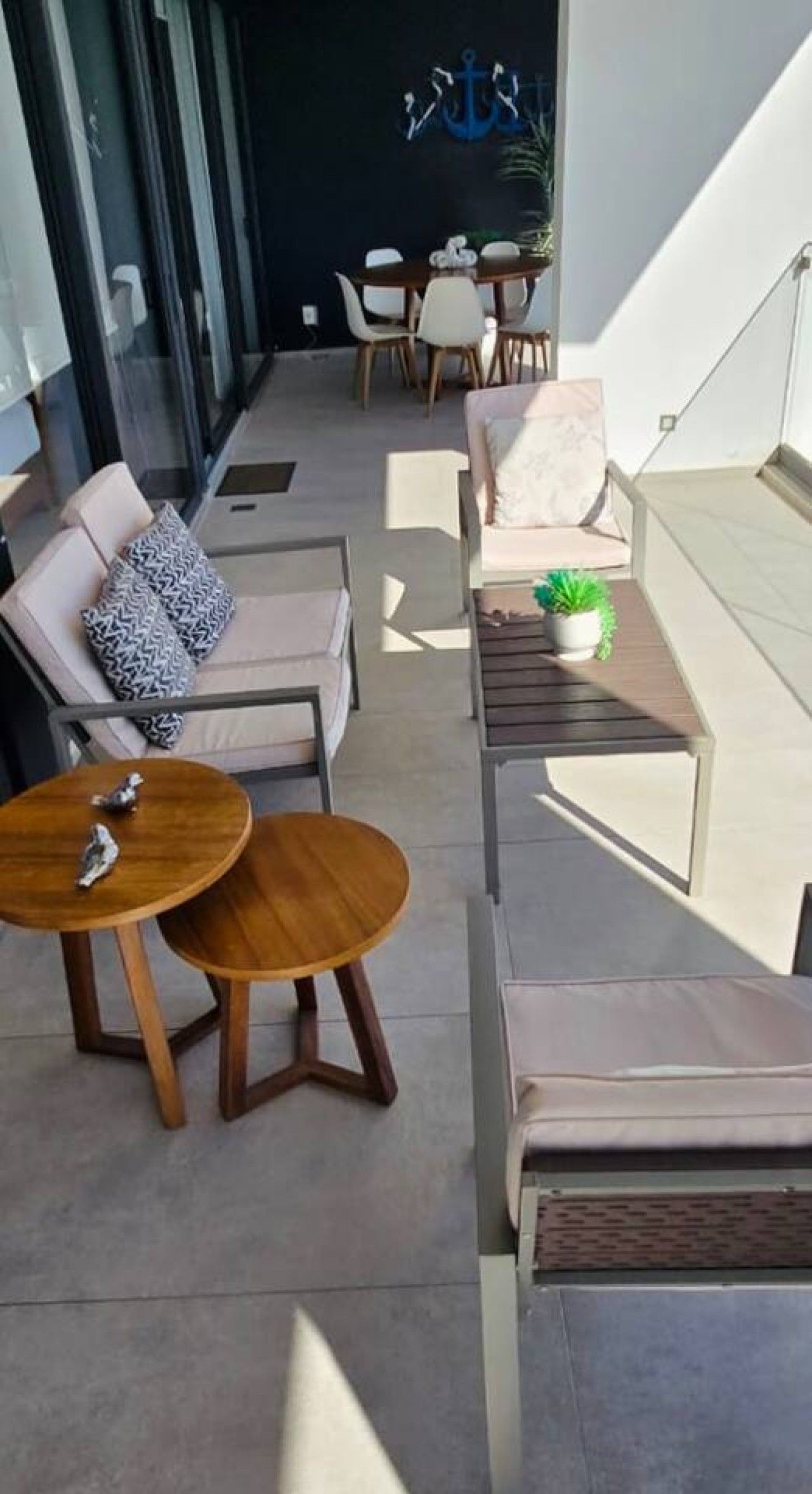 Un espace extérieur moderne aménagé avec un canapé, deux tables rondes et une plante en pot.