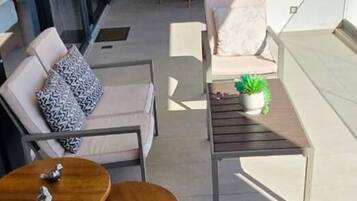 Un espace extérieur moderne aménagé avec un canapé, deux tables rondes et une plante en pot.
