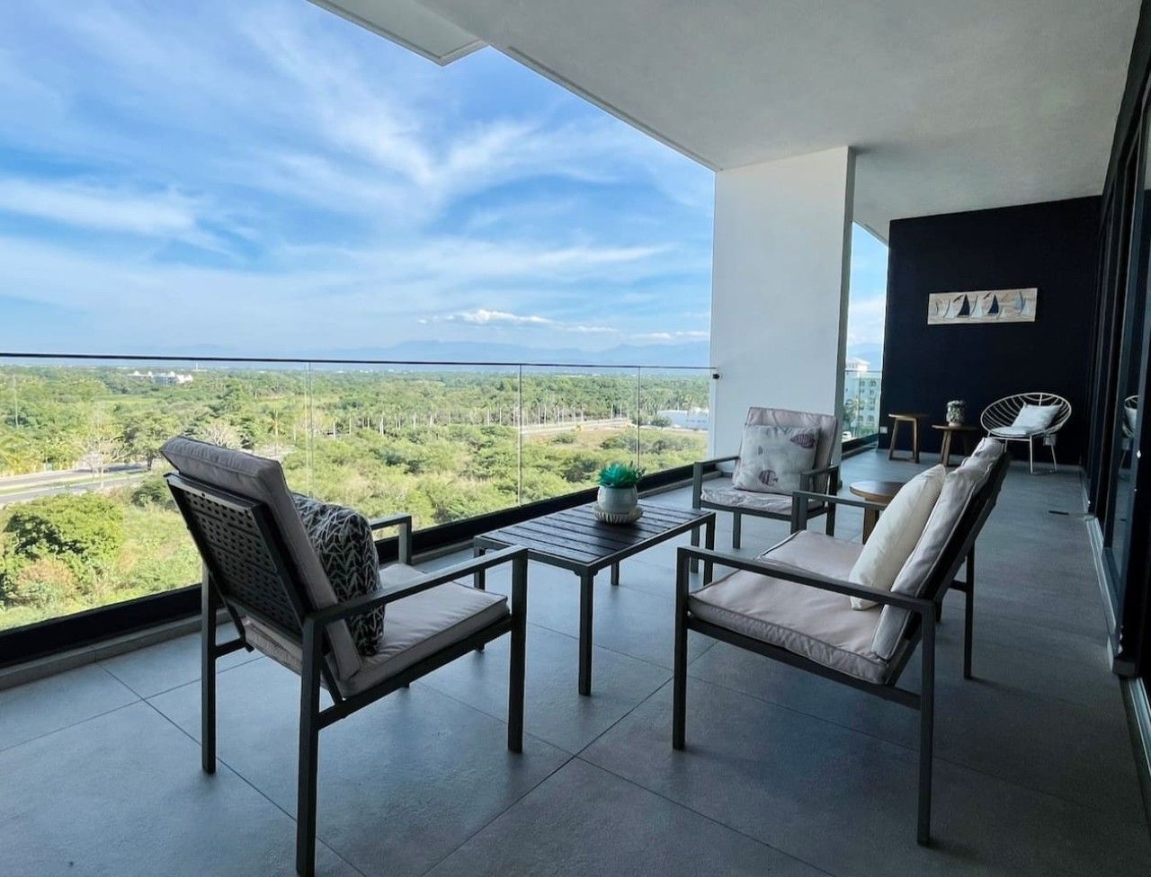 Un balcon donnant sur un paysage verdoyant et un ciel dégagé.