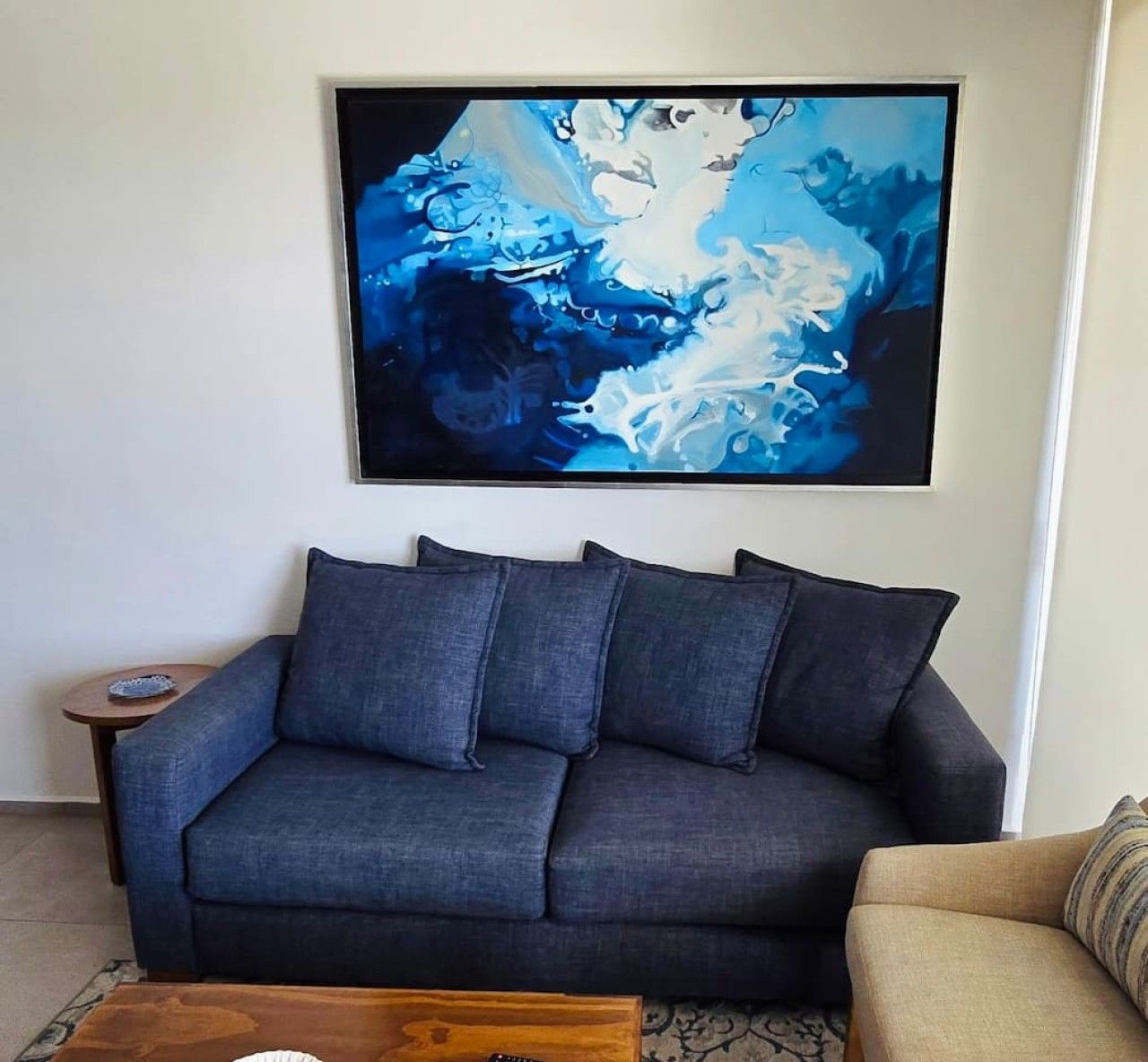 A living room with a dark blue sofa, a small round table, and a coffee table.