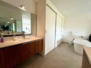 Ein modernes Badezimmer mit großem Spiegel, Waschbecken mit Holzschrank, Badewanne und Toilette.