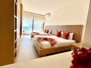 Een moderne hotelkamer met twee bedden, een houten hoofdbord en uitzicht op de stad.