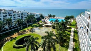 Un complexe hôtelier doté d’une piscine, de palmiers et offrant une vue sur l’océan.
