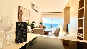 Une chambre d’hôtel moderne dotée d’un coin repas, d’une vue sur l’océan et d’un minibar.
