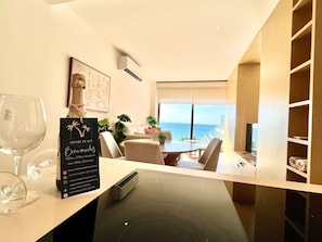 Een moderne hotelkamer met een zithoek, uitzicht op zee en een minibar.