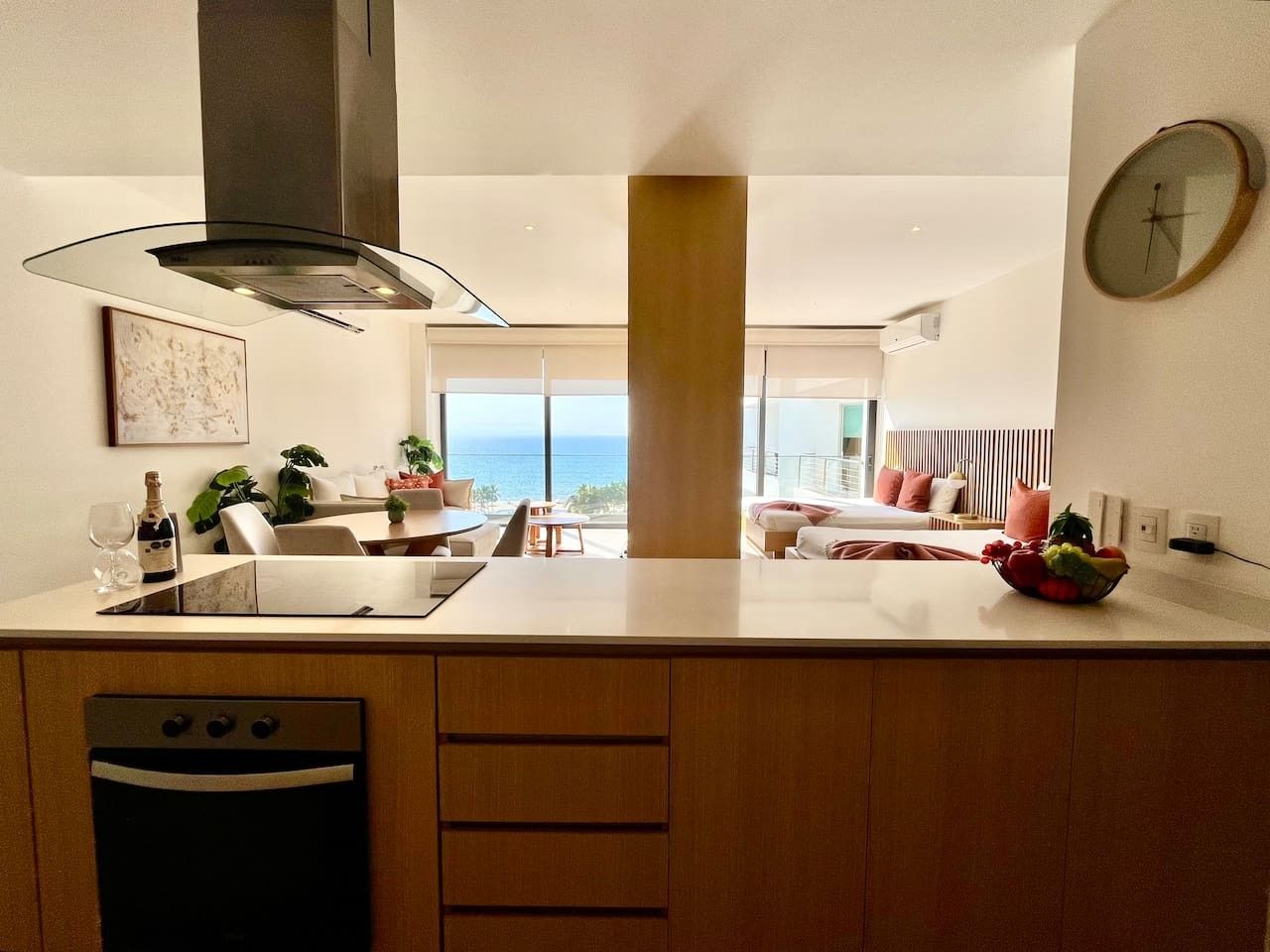 A modern kitchen with a central island, a built-in oven, and a view of the ocean.
