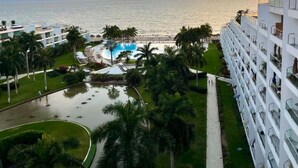 Un complexe hôtelier doté d’une piscine, de palmiers et offrant une vue sur l’océan au coucher du soleil.