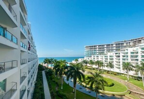 A multi-story hotel with balconies, a pool area, and a view of the ocean. - Wake Up to Ocean Views – Aria Nuevo Vallarta (Nuevo Vallarta)