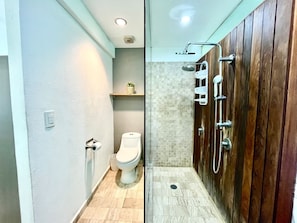Een badkamer met toilet, een douchecabine met glazen deur en een houten wastafelmeubel.