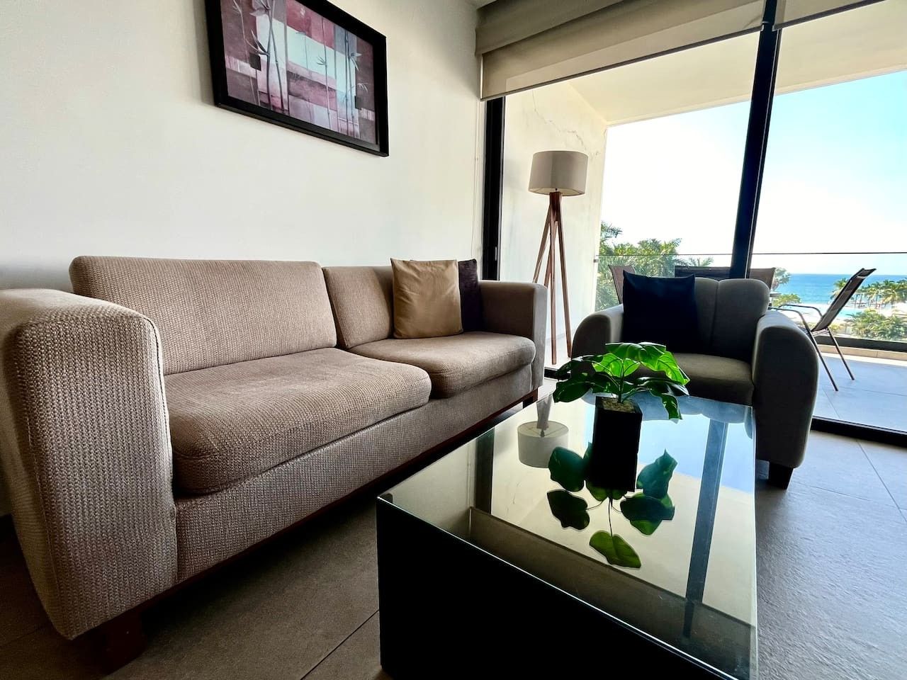 Uma sala de estar moderna com um sofá, uma mesa de centro com uma planta e vista para o exterior.