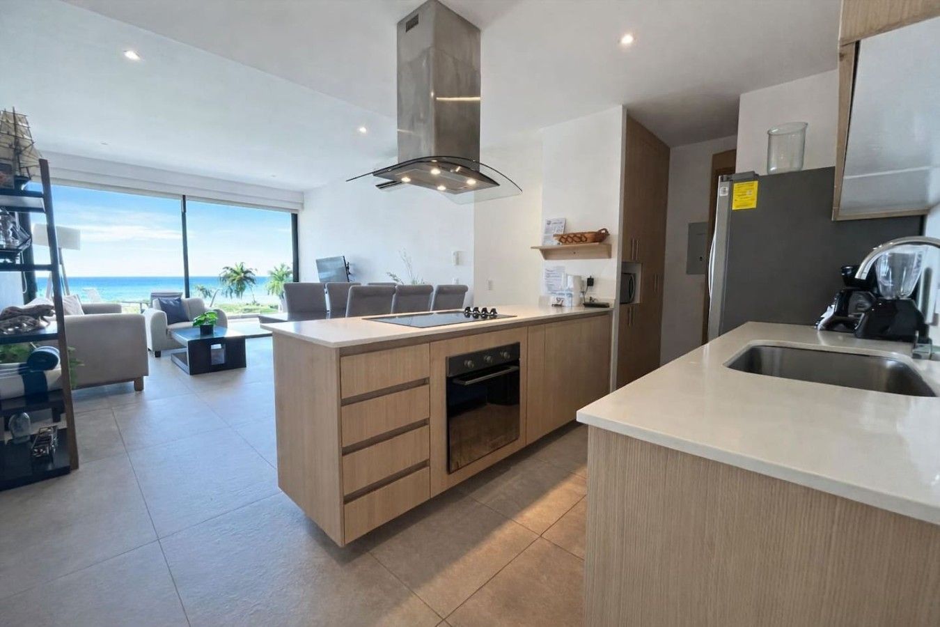 Cozinha moderna com ilha central, forno embutido e vista para o oceano.