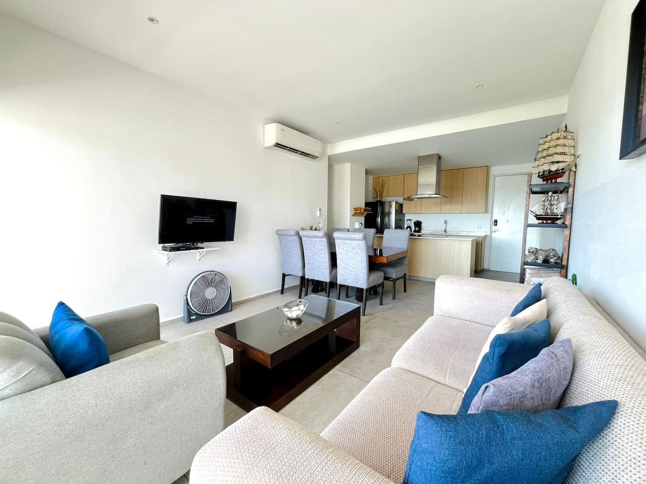 A modern living room with a sofa, coffee table, and a flat-screen TV.