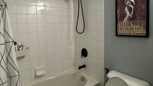 A bathroom with a bathtub, toilet, and a showerhead.