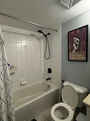 A bathroom with a bathtub, toilet, and a showerhead. - DT Townhouse Room Steps to Transit (Toronto)