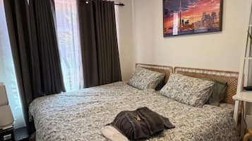 Une chambre à coucher avec un lit double, une table de chevet, une lampe, un tableau et une fenêtre avec des rideaux.