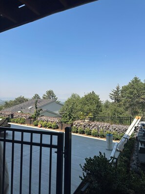 Ein Balkon mit Blick auf eine angelegte Grünfläche, ein Gebäude und Bäume.