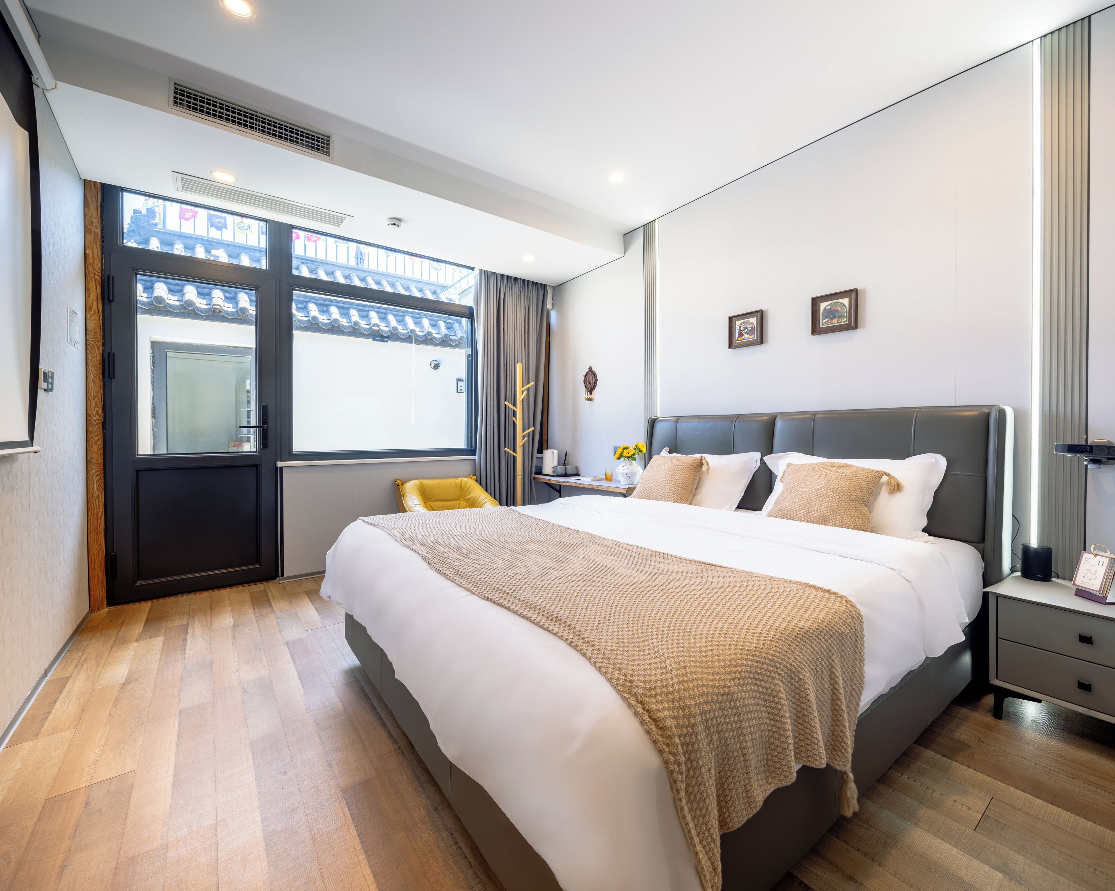 Una habitación de hotel moderna con una cama grande, una mesita de noche y cortinas que dan a vistas exteriores.