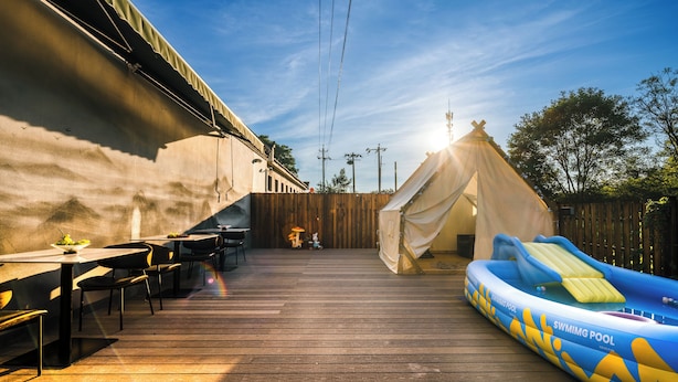 A wooden deck with a dining table and chairs, a tent, and an inflatable swimming pool. - Harbor City (Universal Beijing Resort) (Tongzhou District, Beijing)