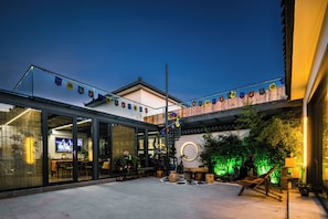 A courtyard with a glass enclosure, outdoor seating, and a neon sign. - Harbor City (Universal Beijing Resort) (Tongzhou)