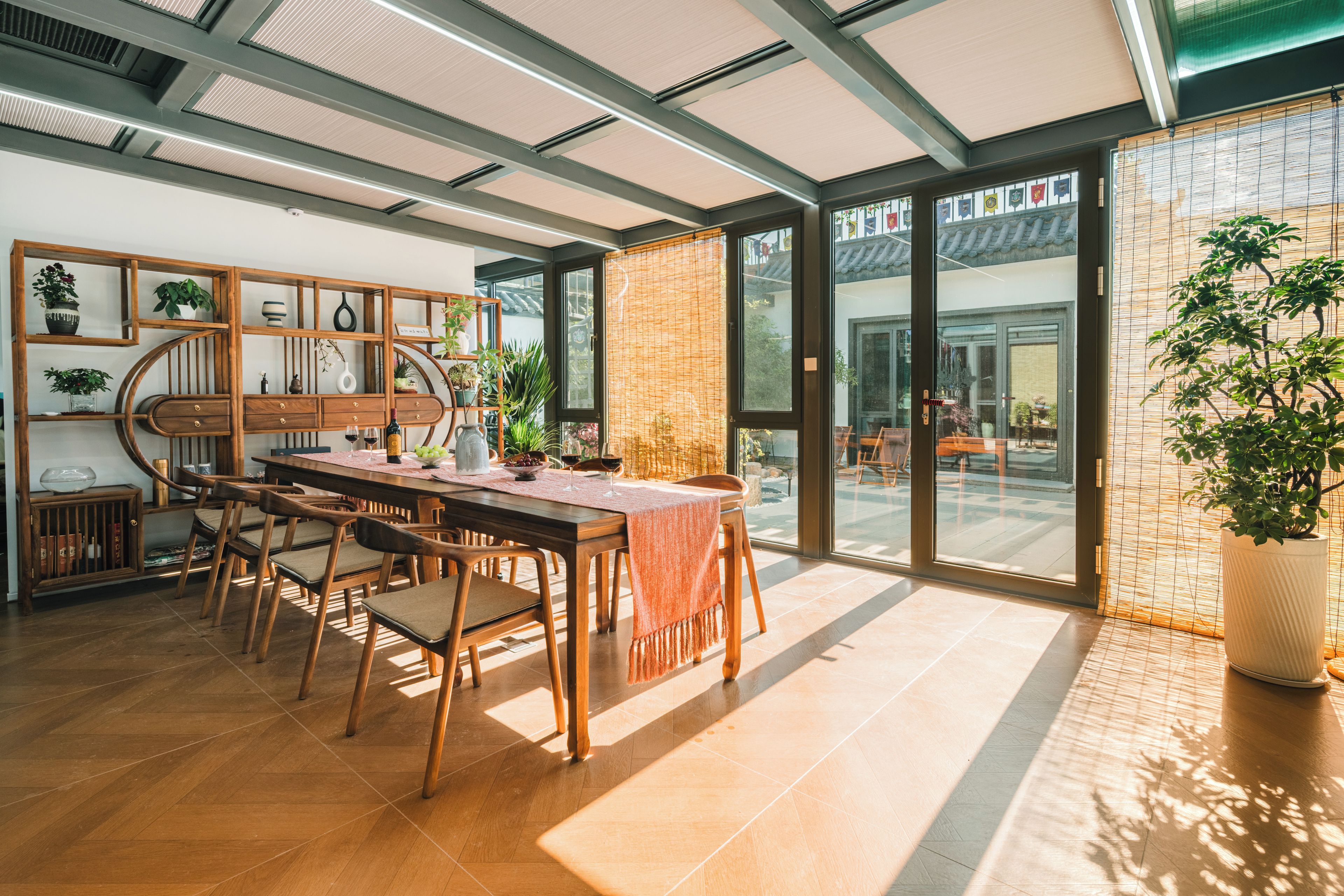 Un comedor con mesa y sillas de madera, un aparador buffet y un ventanal con vistas al exterior.