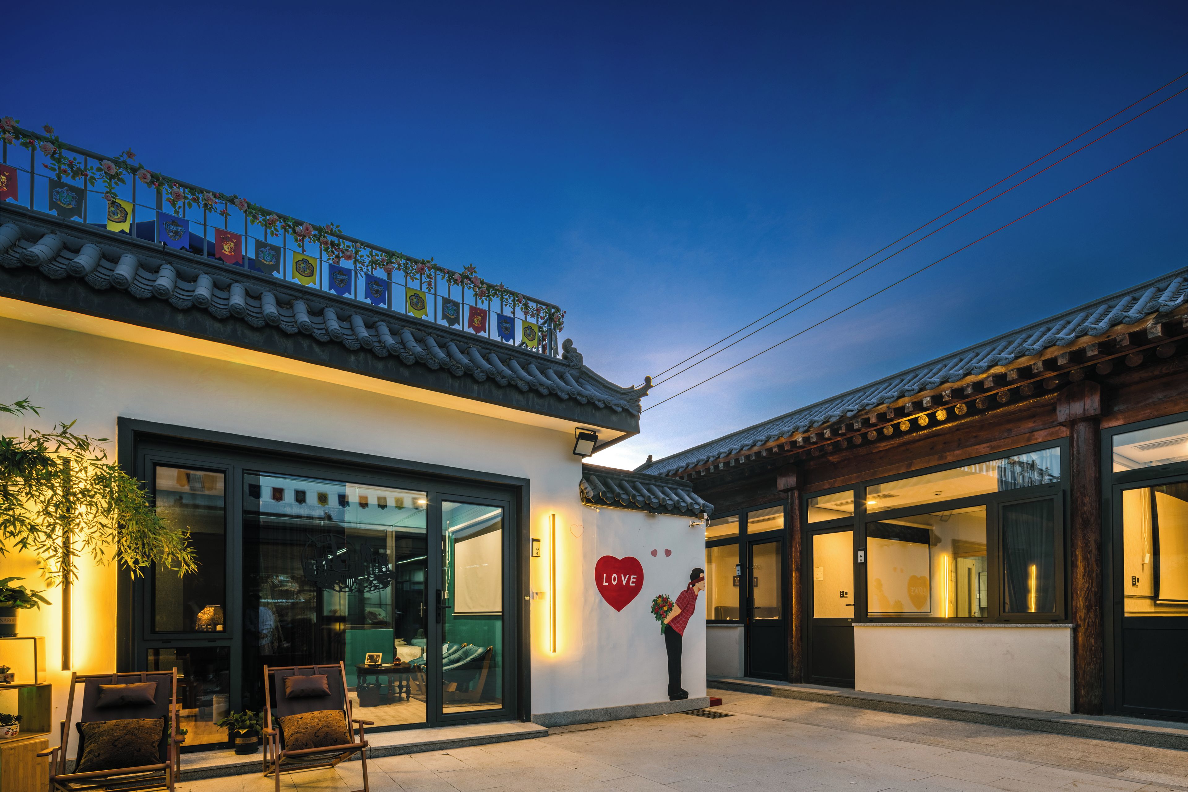 A traditional building with a modern entrance, a balcony with flags, and a heart-shaped decoration.