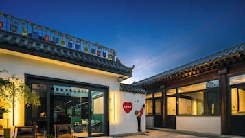 A traditional building with a modern entrance, a balcony with flags, and a heart-shaped decoration.
