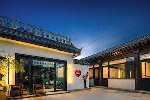 A traditional building with a modern entrance, a balcony with flags, and a heart-shaped decoration. - Harbor City (Universal Beijing Resort) (Tongzhou)