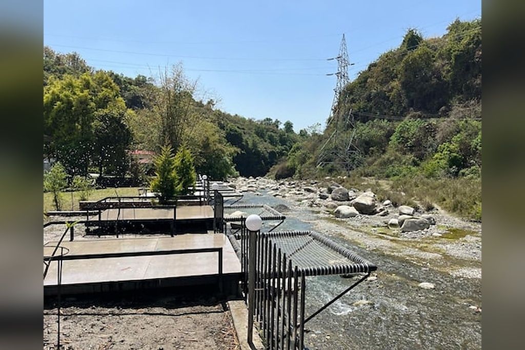A river with a metal railing and a concrete platform.
