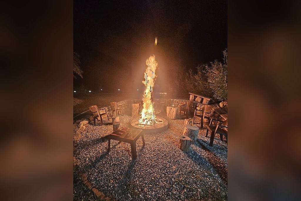 A fire pit with seating around it, set on a gravel surface.