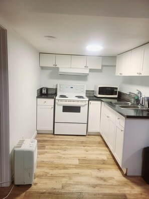 A compact kitchen with white cabinets, a stove, a microwave, and a sink. - Central Cozy Haven! Private Room, Self Check-In, U of A, NAIT (Edmonton)