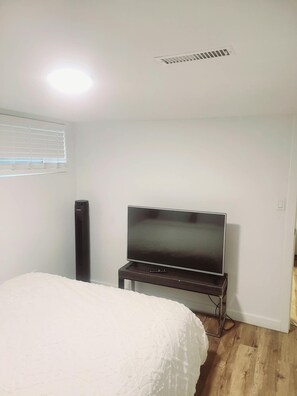 A bedroom with a bed, a television on a stand, a window with blinds, and a vent on the ceiling. - Central Cozy Haven! Private Room, Self Check-In, U of A, NAIT (Edmonton)