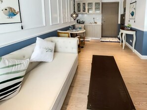 Un salon avec un canapé, une table à manger et, au fond, un coin cuisine.