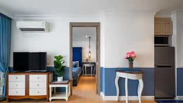 A modern living room with a flat-screen TV, a wooden cabinet, a potted plant, and a small table with a vase of flowers.