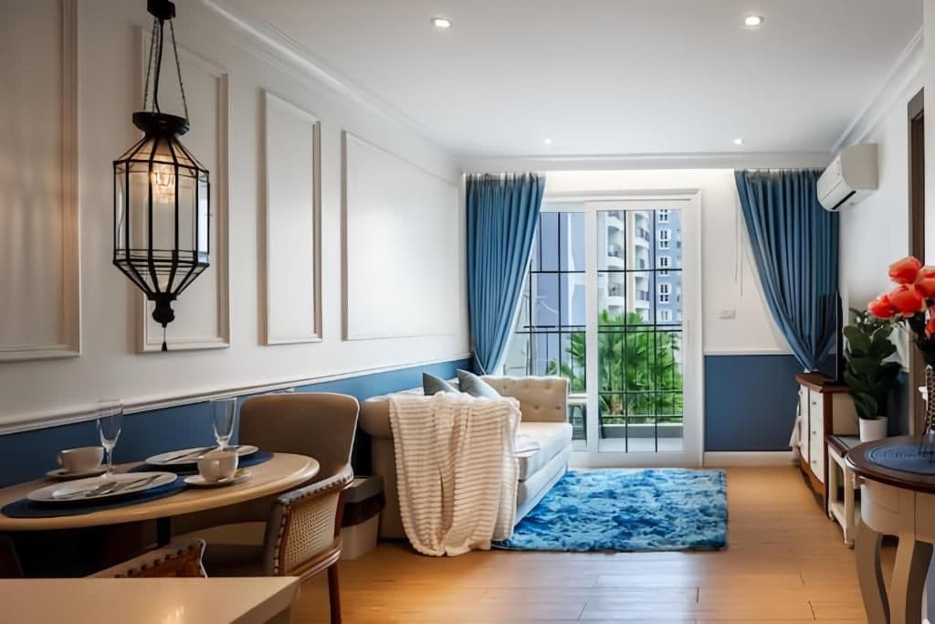 Comedor con mesa dispuesta para dos, sofá y vista al exterior a través de una ventana.