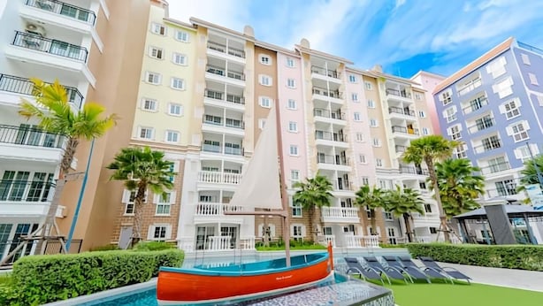 Una piscina con un velero, rodeada de edificios residenciales de varios pisos.