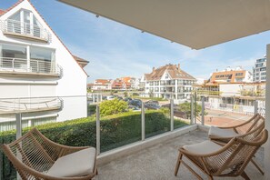 A balcony with wicker chairs, a view of a residential area, and a clear sky. - Elegant Apartment Near Casino (Knokke-Heist)