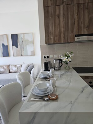 A modern kitchen with a marble countertop, a coffee maker, and a toaster. - Brand-new, elegant 1-bedroom apartment with stylish interiors and luxurious (Muscat)