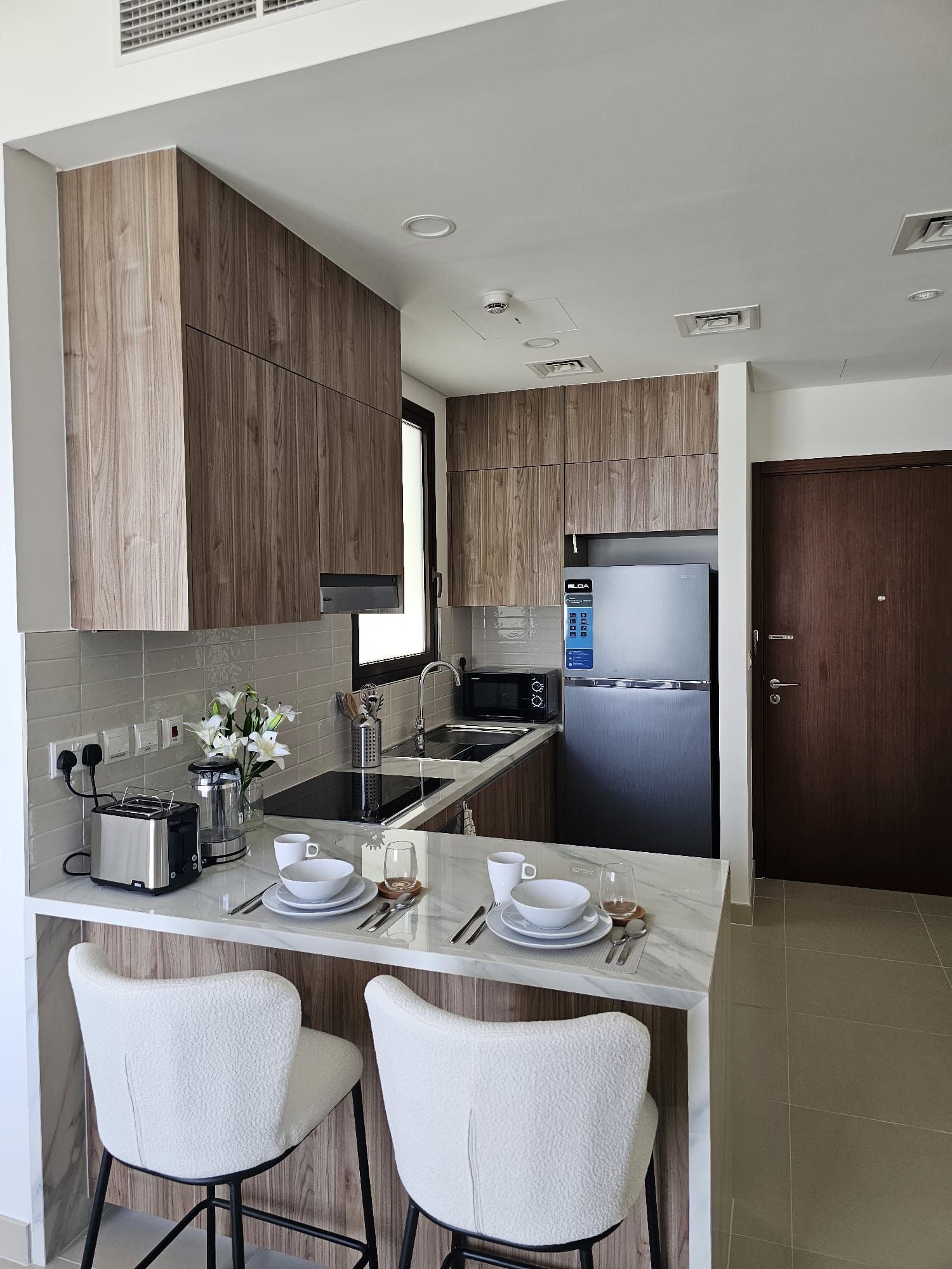 A modern kitchen with wooden cabinets, stainless steel appliances, and a marble countertop.