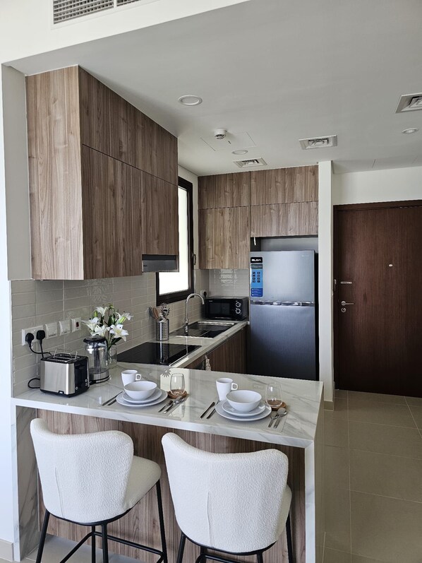 A modern kitchen with wooden cabinets, stainless steel appliances, and a marble countertop.