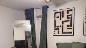 A bedroom with a bed, a sofa, a ceiling fan, and a mirror. - Historic STL Home near Wash U/Massive Backyard (University City)