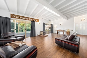 A spacious living area with leather sofas, a fireplace, and a large window overlooking greenery.