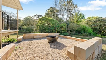 A landscaped outdoor area with a fire pit, wooden deck, and surrounding vegetation.