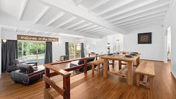 A spacious room with a wooden dining table, a sofa, and a bench. A sign reads 'Welcome to the Farm.'