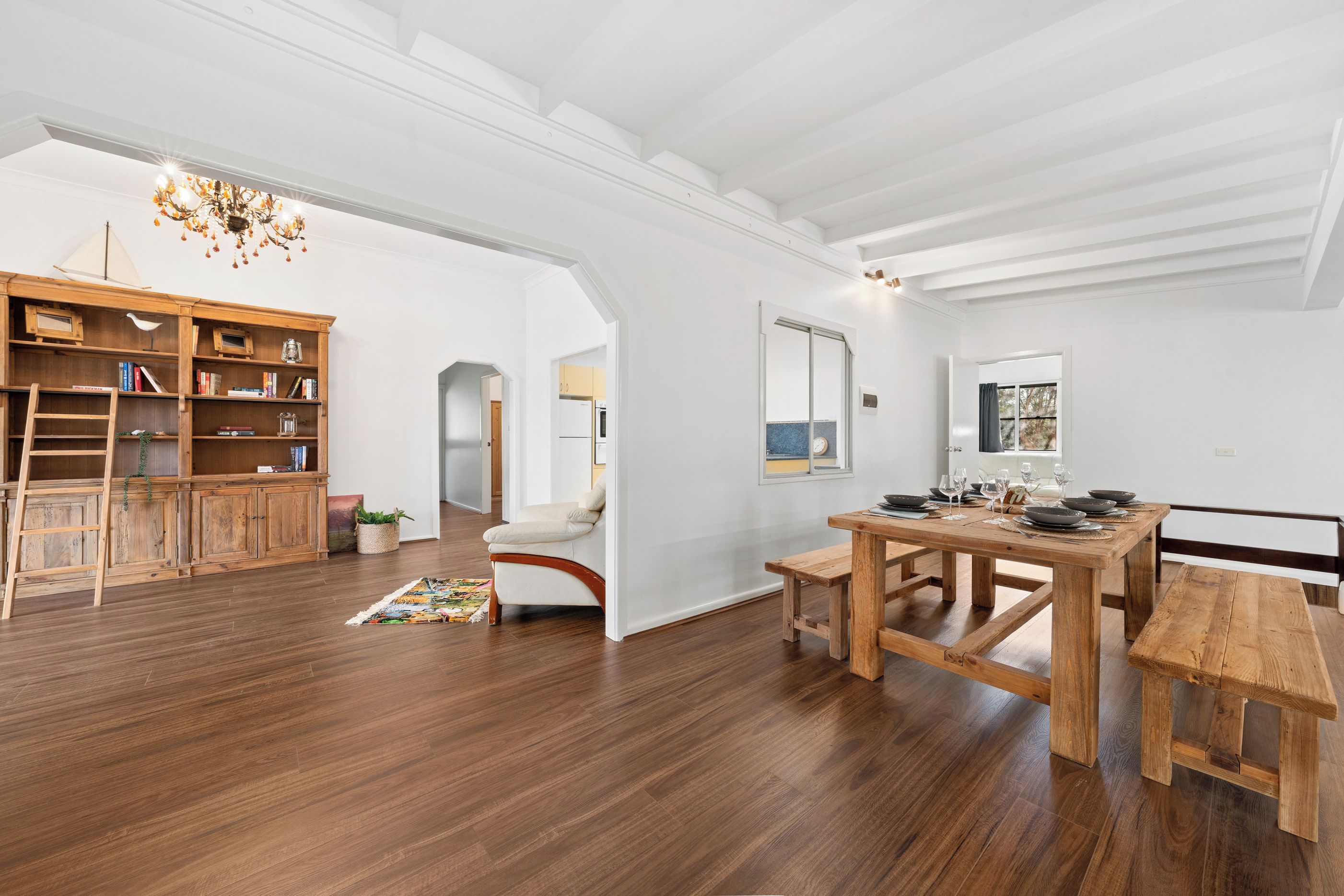 Amplia habitación con una mesa de comedor de madera, una estantería y un candelabro.