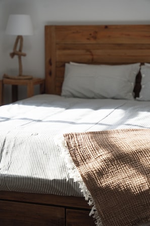 A bed with a wooden headboard, a striped pillow, and a textured blanket.